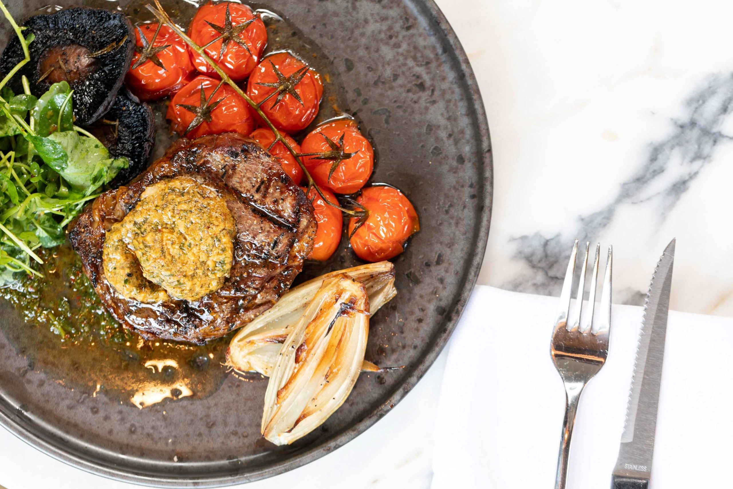 Ateak grilled tomatoes and garnish on a plate on a marble table